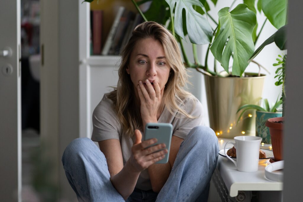 depressed unhappy woman woman looking at mobile phone screen stunned with negative news