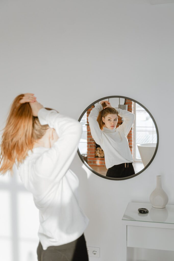 girl tidies up in front of a round mirror