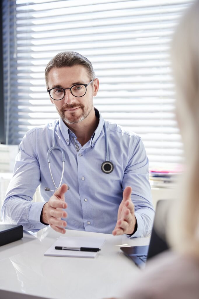 mature female patient in consultation with doctor sitting at desk in office