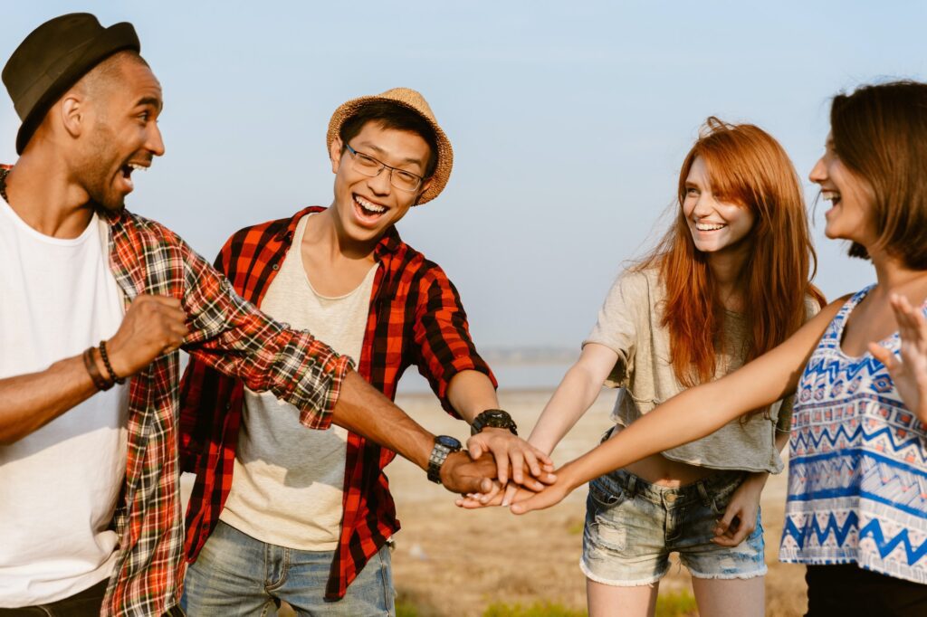 young multiracial friends holding hands and laughing together