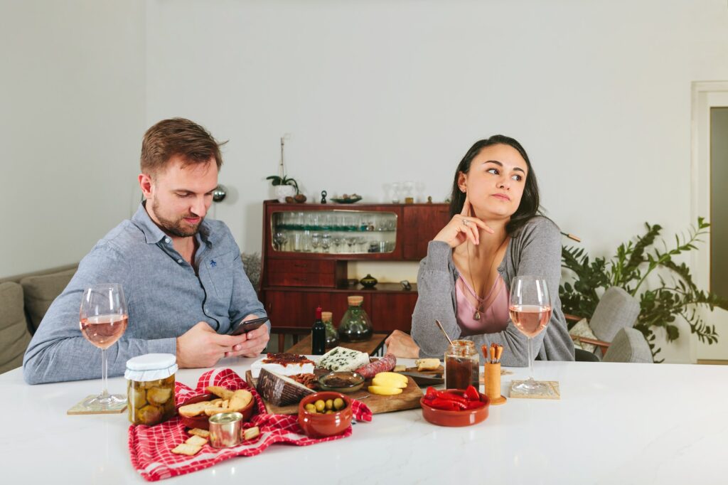 bored woman looks away while on date with a man with nomophobia