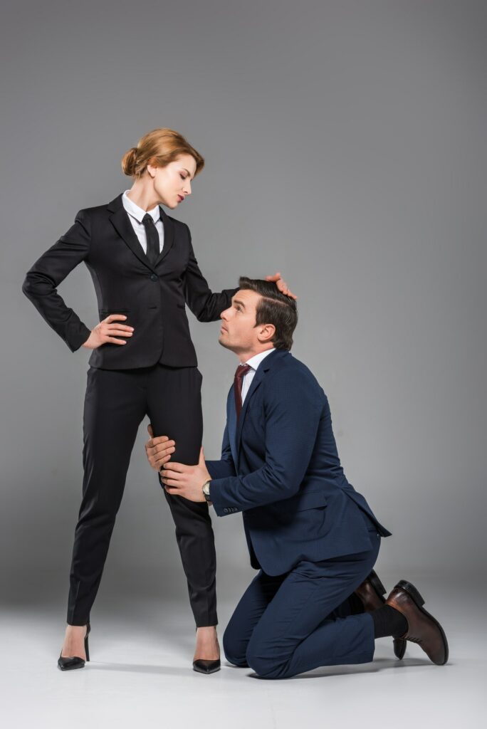 female boss dominating over scared businessman, isolated on grey, feminism concept