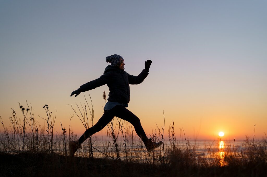 Woman jumping in the evening on sunset background. Motivation