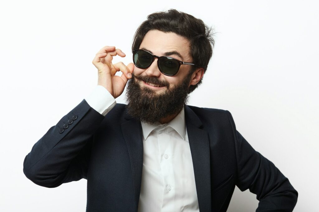 Smiling man with a beard touching his mustaches